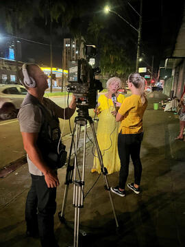 Fotografia de Equipe da TV Anhanguera enquanto realiza entrevista com Condessa Valéria Vaz sobre atividade social junto à pessoas em situação de rua na Avenida Independência em Goiânia