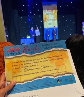 Exibição de diploma de honra ao mérito ao Cabaré das Divas em solenidade do Prêmio Buritis 'Destaques da Cultura Goianiense' de 2024, no Teatro Goiânia Ouro