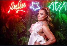 Retrato de Barbará Bombom em frente a painel verde com luzes neon